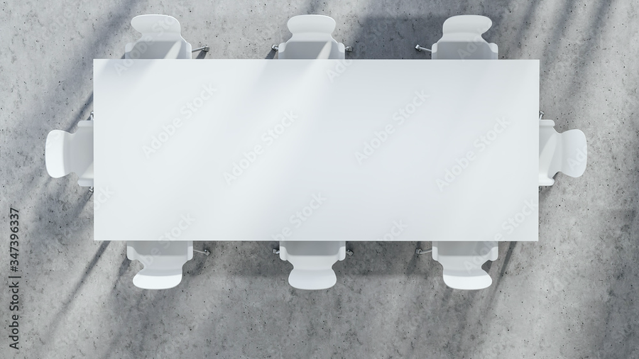 Top-down view of a white conference table and chairs on a concrete floor